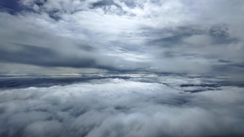 An iimmersive pilot’s eye view from the cockpit of a jet airplane while flying at supersonic speed between layers of darkening stratus clouds. 4K shot.