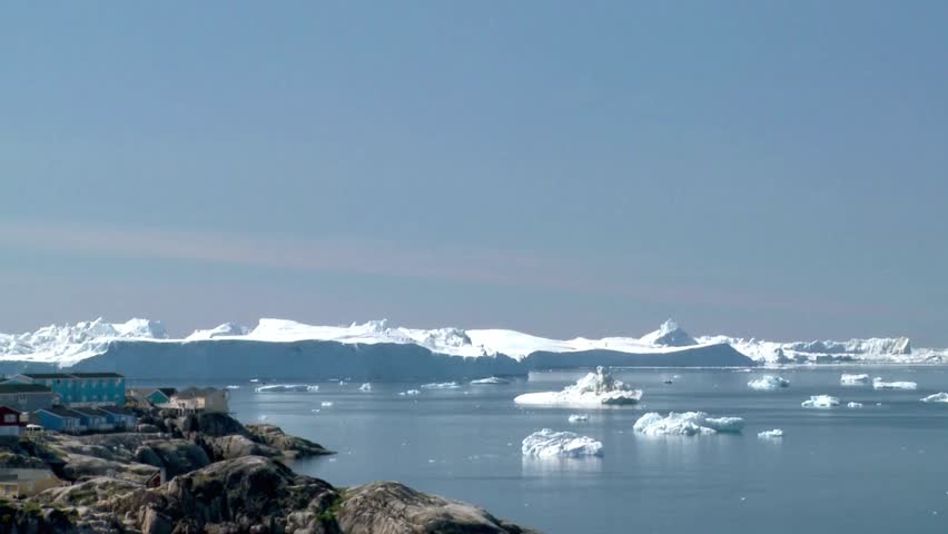 Scenic view of icebergs floating in the arctic ocean near a coastal settlement