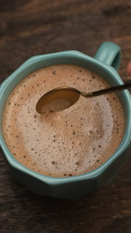 Female hand stir coffee with thick foam, close up