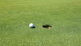Golfer ready to putt golf ball towards hole on manicured green grass. Clear focus on ball and hole with bright outdoor lighting enhancing details. - Powered by Shutterstock - Get 15% off with code: PIKWIZARD15