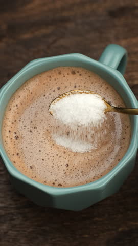 Female hand stirring sugar in mug of coffee. coffee with white sugar