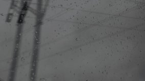 A POV shot from a train window on a rainy day, showing water droplets and passing scenery, including power lines, trees, and blurred lights - Powered by Shutterstock - Get 15% off with code: PIKWIZARD15