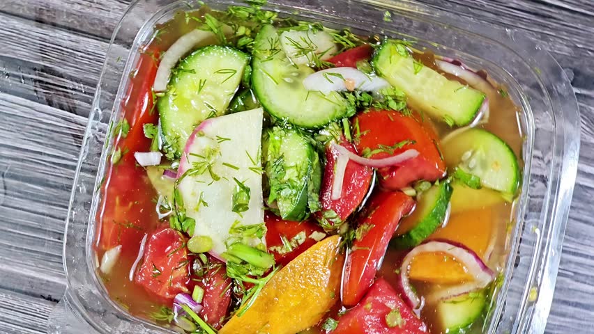 The Traditional Arabic fresh green salad with slices of cucumber, tomatoes, green dill, carrot, onion and radish mixed together, pieces of fresh vegetables mixed together, healthy food dietary concept