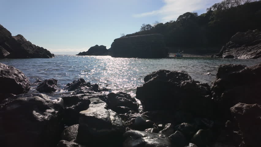 The tide going out showing a rocky beach with a boat moored in the harbour of Stackpole Quay on the Pembrokeshire Coast, Wales.