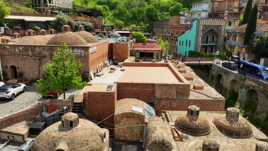 A detailed aerial video of the Abanotubani sulfur bath district in Tbilisi, showing the iconic brick domes and surrounding colorful houses