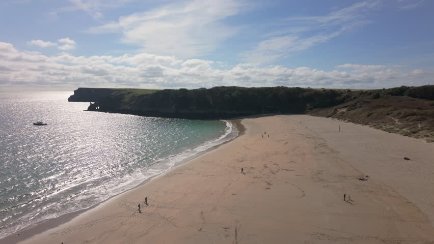 Establishing shot of Barafundle Bay Beach on the Pembrokeshire coast, Wales on a bright sunny summer day with a calm sea.
