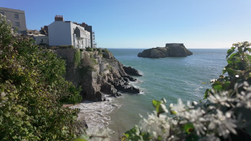 The south beach of the Welsh harbour town of Tenby on a summer day at high tide with St Catherines Island in the distance.