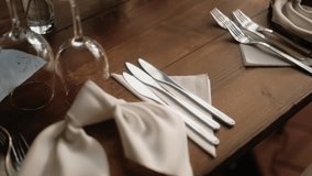 Close-up shot of neatly arranged silverware, folded napkins, and glassware on a wooden dining table, in soft natural light - Powered by Shutterstock - Get 15% off with code: PIKWIZARD15