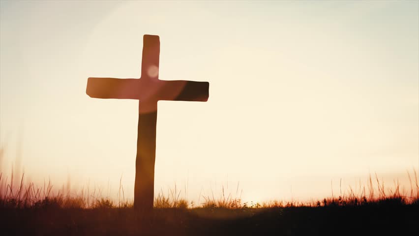 Silhouette of wooden cross standing on a hill at sunset. Religion and faith
