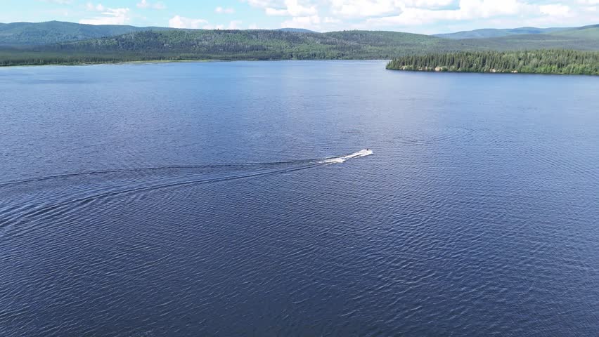 Experience the thrill of speedboating across a serene lake surrounded by lush green hills in Alaska perfect for adventure travel and water sports videos