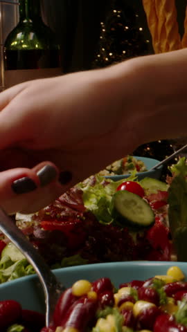 Vertical slow motion video cinematic scene hands serving salad pouring red wine festive table cozy warm light concept authentic family holiday lifestyle thanksgiving christmas dinner mood