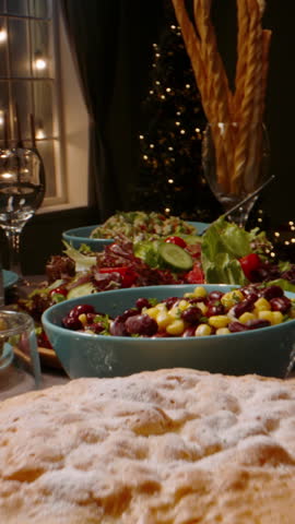 Vertical slow motion video cinematic scene hands serving salad pouring red wine festive table cozy warm light concept authentic family holiday lifestyle thanksgiving christmas dinner mood