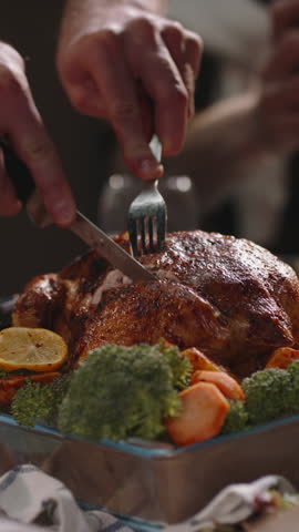 Vertical video cutting piece of roasted turkey on festive table with vegetables holiday dinner thanksgiving celebration christmas feast family gathering delicious food cozy light