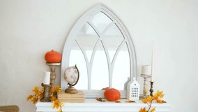 Autumnal mantel decor with pumpkins, candles, autumn leaves, and globe reflecting in arched mirror - Powered by Shutterstock - Get 15% off with code: PIKWIZARD15