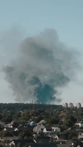 A large column of thick, black smoke rises from a burning building after a ballistic missile strike. Fire and bombing during the war between Ukraine and Russia. Political crisis and conflict.
