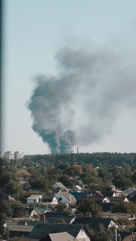 A large column of thick, black smoke rises from a burning building after a ballistic missile strike. Fire and bombing during the war between Ukraine and Russia. Political crisis and conflict.