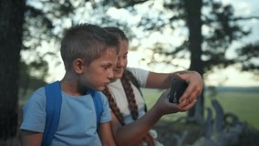 Girl and boy share selfie moment in forest. Tablet in hand, tablet open. Sibling smiles, sibling laughs. Children enjoy quiet screen time. Selfie repeats. Forest still, girl laughs, boy smiles. - Powered by Shutterstock - Get 15% off with code: PIKWIZARD15