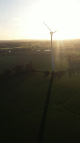Minimal composition: single turbine and wide sky at sunset. Vertical 9:16—perfect for titles, copyspace, and clean energy themes.