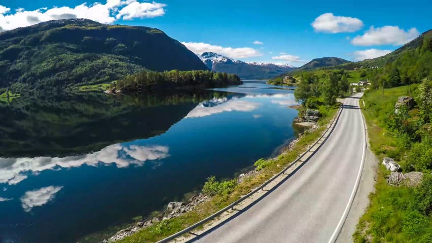 Scenic mountain road and lake reflections in sunny weather
