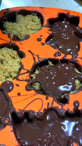 Final chocolate layer covers kunafa filling in spooky silicone mold. Glossy, rich coating poured by hand completes this festive diy treat smooth, sweet and ready to chill into halloween candy.