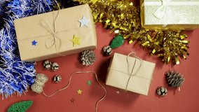 woman hand tying a  ribbon on a craft gift box with pinecones, glitter stars, and tiny Christmas trees on a warm red background - Powered by Shutterstock - Get 15% off with code: PIKWIZARD15