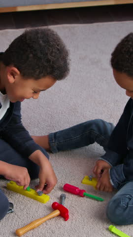 Two African American boys kids playing repair tools toys family sons at home children brothers friends on floor play construction game together spending weekend in apartment happy relationship bonding