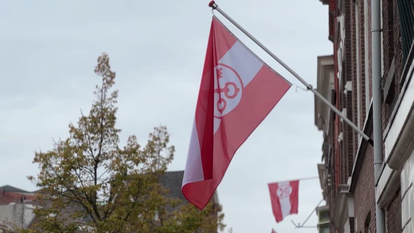 Close-up of the red and white Leiden city flag waving on a historic Dutch building under a cloudy sky, symbolizing city pride and heritage - Leidens ontzet, 3 oktober