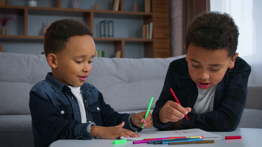 Two African American boys kids drawing picture together psychology art therapy at home sons siblings friends children draw with colorful markers in apartment ethnic family artwork hobby education