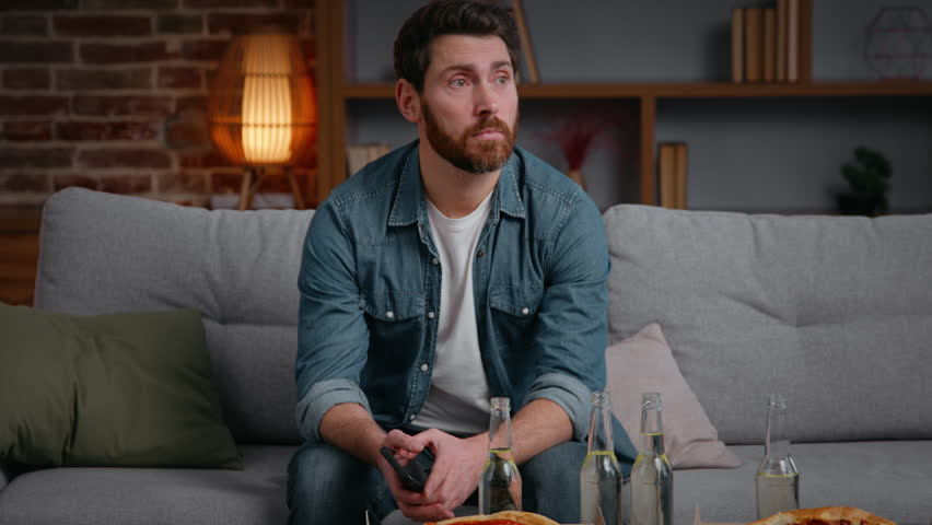Caucasian middle-aged frustrated disappointed man at home party canceled with pizza chips stress alone lonely male guy on couch suffering without no friends birthday loneliness isolation quarantine