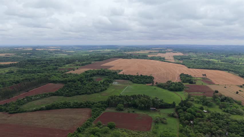 Aerial fly over agricultural fields alternating with green forested patches and plantations, Campichuelo, Paraguay.
