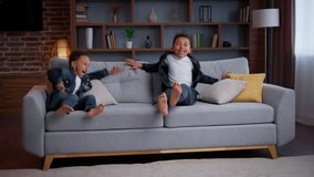 Happy African American little boys jumping on couch joyful positive ethnic children carefree active siblings sons kids running in living room jump on comfy sofa playing family having fun joy indoors - Powered by Shutterstock - Get 15% off with code: PIKWIZARD15