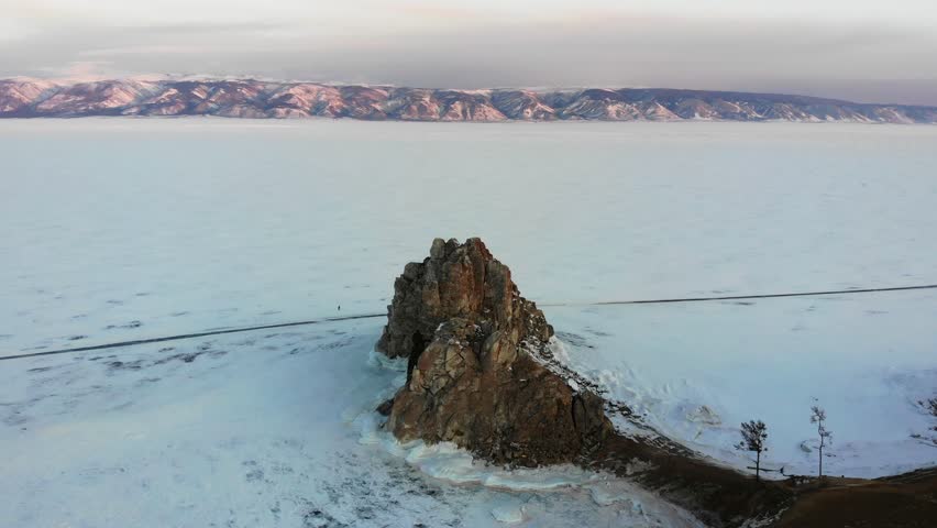 Lake Baikal in the snow. Flying around Shamanka rock, Cape Burkhan from the air. A popular tourist destination on the island of Olkhon.