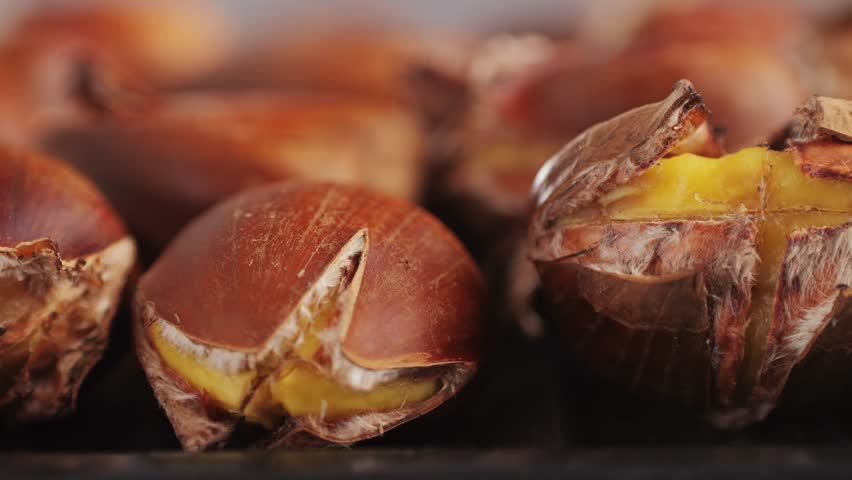 Grilled Fresh chestnut, supermarket food, grill Oven roasted chestnuts with sliced peel on wooden board, spanish traditional winter dish.