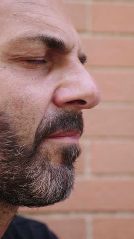 Vertical shot of a middle-aged man with a bald head and short beard in profile, showing a contemplative and strong expression. His eyes reflect deep thoughts and determination