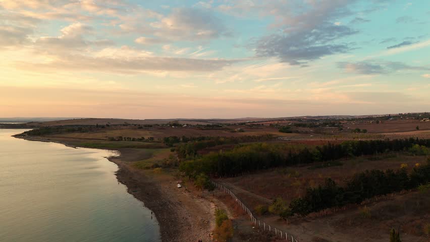 A marsh landscape shimmering with the reflection of twilight. The Atmosphere 4K drone shot shows the magical effect of the sunset over the moody, wetlands nature.