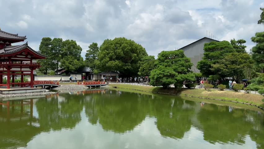 Byodoin, Uji, Kyoto, Japan: Tang Dynasty-style architecture and garden waterscapes blend, showcasing Heian-period Eastern religious architectural art among red bridges and green trees.