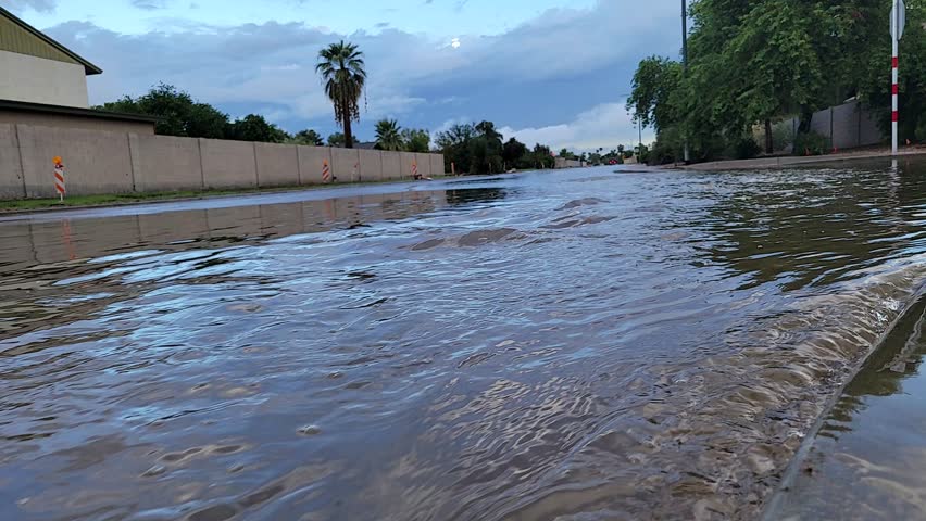 Rain water rushing downstream along flooded road after early morning autumn storm, Phoenix, Arizona