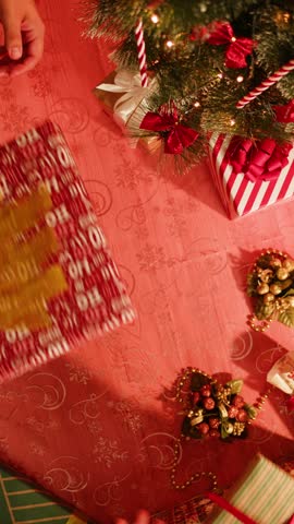 Friends giving presents to each other top view, celebrating new year, sitting at dining table. International young people making surprises. Diverse students during christmas party at home. 