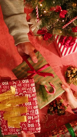 Friends giving presents to each other top view, celebrating new year, sitting at dining table. International young people making surprises. Diverse students during christmas party at home. 