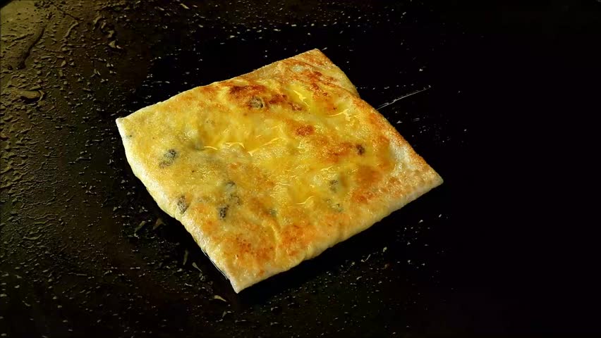 Footage of Delectable Banana and Raisin Fillings Roti Being Cooked on a Griddle