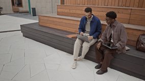 Young biracial programmers dressed in casual looks sitting on wooden bench and discussing new startup - Powered by Shutterstock - Get 15% off with code: PIKWIZARD15