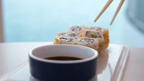 Sushi roll dipped in soy sauce on black background close-up vertical video. Man eats sushi roll with chopsticks while soaking it in sauce. - Powered by Shutterstock - Get 15% off with code: PIKWIZARD15