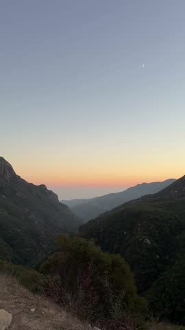 Sunset over Pacific Ocean near Los Angeles with golden light reflecting on the coastline and mountain silhouettes under clear California sky.