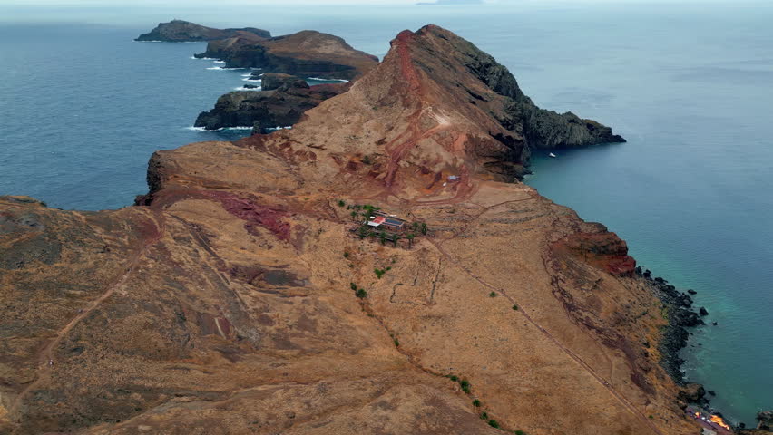 Aerial rugged coastal landscape under cloudy sky. Picturesque morning nature on island. Blue ocean waves washing rocky shore. Tranquil deep turquoise water. Natural beauty of serene seaside scene 