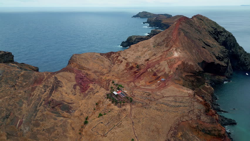 Ocean washing volcanic rocks drone view. Breathtaking cliffs at deep blue sea. Aerial of brown island formation under cloudy sky. Calm rippling sea water rolling on high picturesque shore panorama