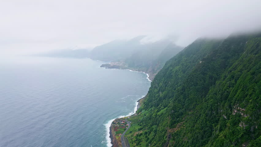 Aerial green mountains marine landscape. Drone view high island cliffs covered vivid vegetation under low clouds sky. Breathtaking panorama lush valleys. Scenic hiking area travel exploration concept