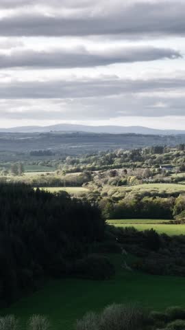 Rolling hills under a cloudy sky. Lush green fields stretch to the horizon.