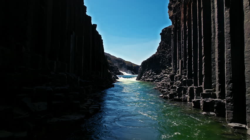 Aerial footage of Stuðlagil Canyon in East Iceland. The glacial river runs through deep basalt formations and volcanic rock walls.
