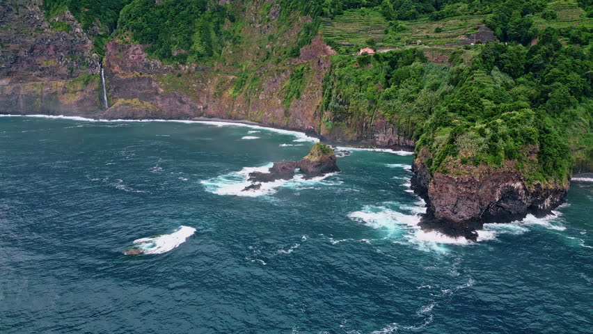 Drone majestic green island landscape. Tranquil coastal view in summer. Blue ocean waves foaming crashing cape. Amazing rock formations at stormy sea. Adventurous hike along serene seaside cliffs