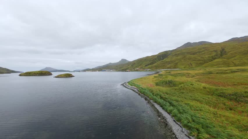 Aerial view of Alaska green coastline. Sea bay, small islands, and mountain range of Unalaska Island, Alaska. Drone footage of wild nature of Dutch Harbor, Aleutian Islands. 